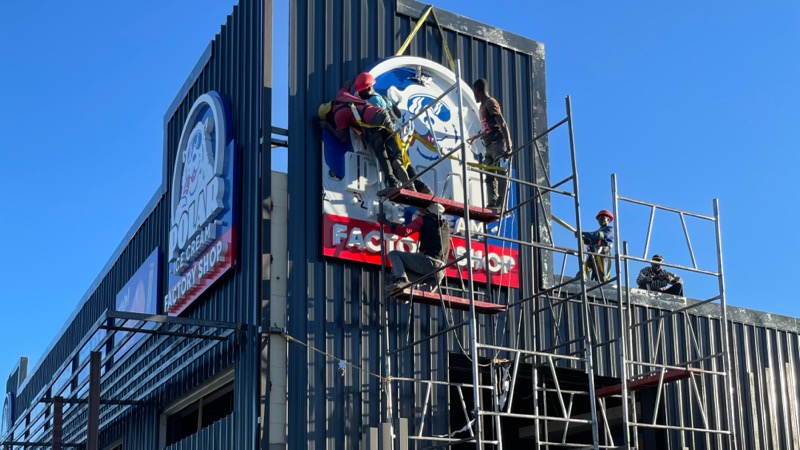 Installers fitting the illuminated Polar Ice Cream sign to the facade.
