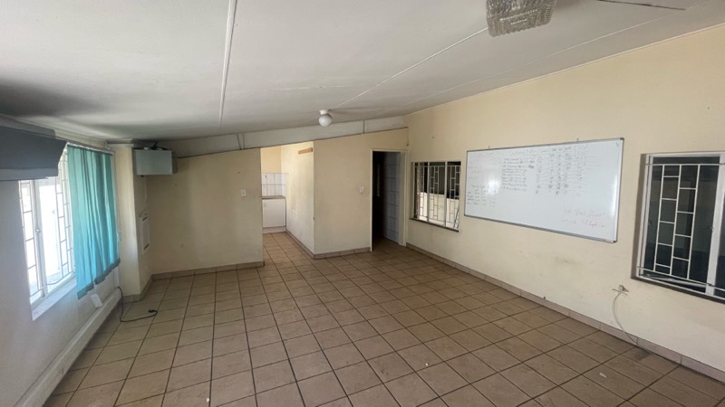 A tiled office room with a whiteboard and curtained window, before the conversion.