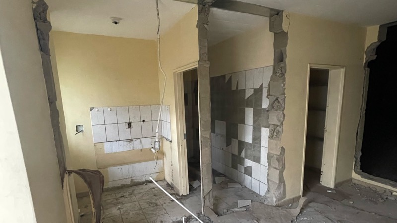 A stripped service area with tiles knocked off the walls and openings cut through.