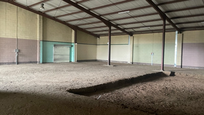 A service trench dug across the sand floor of the empty warehouse.