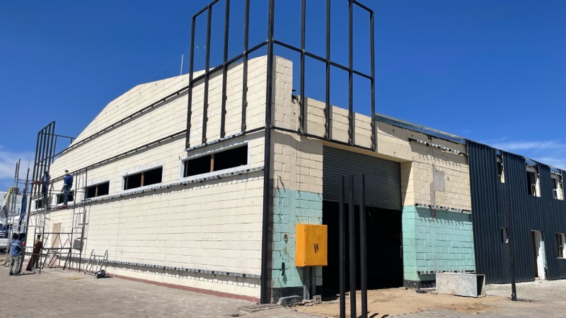 The facade part clad in black, with the steel frame extending above the roofline.