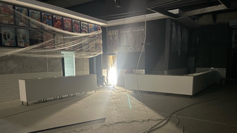 The dark interior with the retail counter being built under work lights.